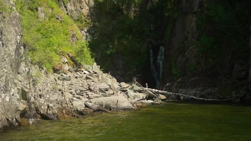 Ein kleiner Wasserstrom fließt aus dem Steinfelsen am Flussufer