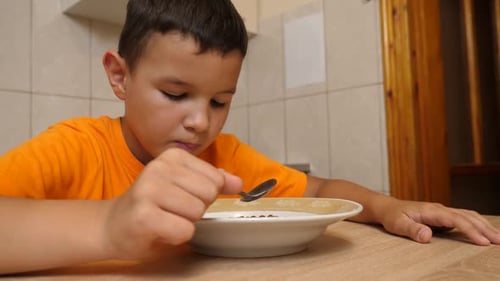 Young Boy Eats Cereal for Breakfast in Kitchen