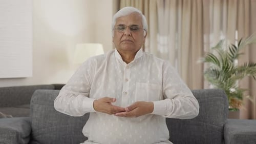 Senior Man Meditating on Couch at Home