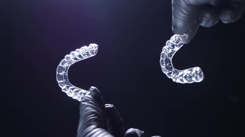 Hands Displaying Clear Plastic Dental Aligners