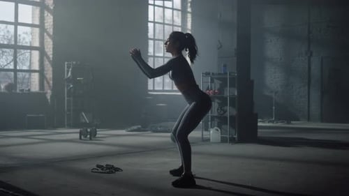 Athletic girl doing squats in fitness gym leg workout training session indoors