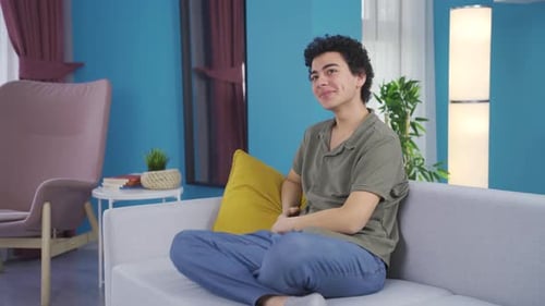 Young Adult Relaxing Comfortably on Gray Sofa