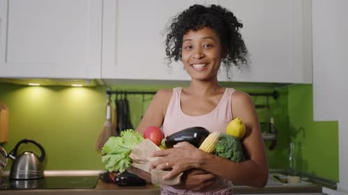 Mujer afroamericana sostiene verduras frescas en una bolsa de papel