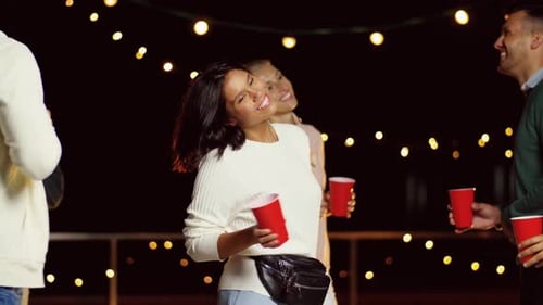 Friends celebrating and dancing at night party outdoors