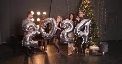 Group Celebrates with 2024 Balloons Near Christmas Tree