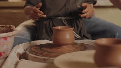 Un potier travaille dans un atelier avec son fils arrête le tour de poterie avec le petit fini
