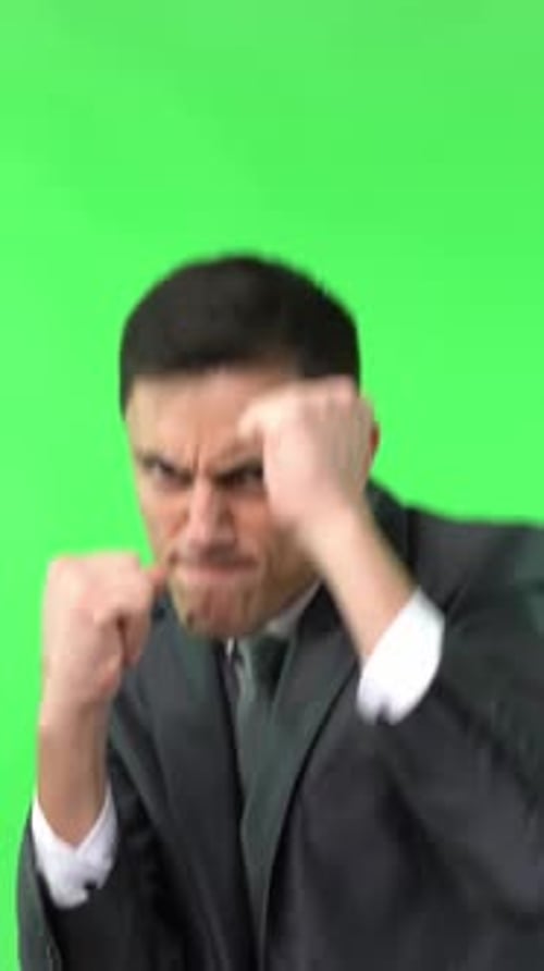 Aggressive Businessman Simulates Boxing Against Green Screen