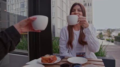 Young Woman Making a Coffee Toast with a Friend at an Outdoor Cafe