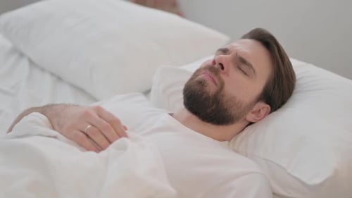 Man Waking Up and Stretching in Bed