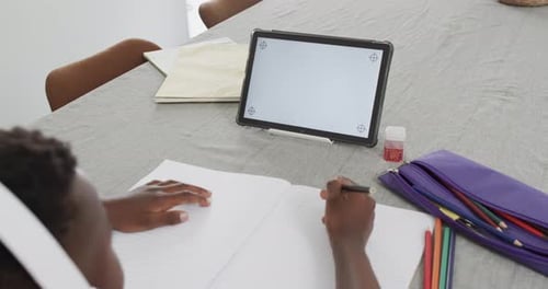 Young Person Studying with Tablet and Notebook