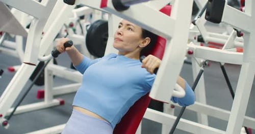 Woman Using Chest Press Machine at the Gym