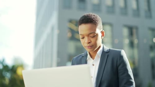 jeune femme d'affaires afro-américaine indépendante assise sur un banc travaillant avec un ordinateur portable dans un parc de la ville