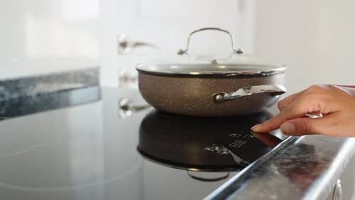 Cooking, includes cooktop, frying pan warms up, close-up in motion. Black stone countertop.