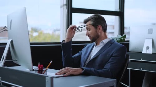 A Professional Man Engaged in Various Tasks While Working in a Modern Office Environment