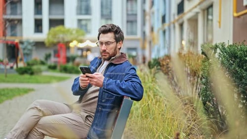 Man Happy Using Phone on Park Bench