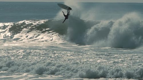 El
surfista está intentando montar una gran ola, pero fracasa. Los deportes extremos y el poder de las olas aplastantes.