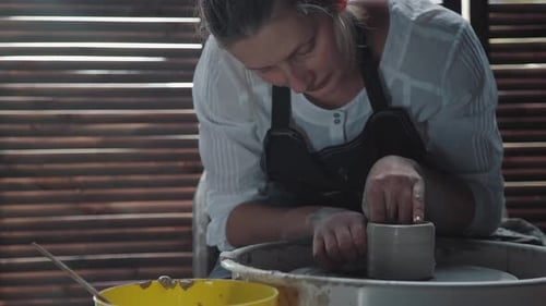Woman Potter Makes a Product From Clay and Works with a Potter's Wheel