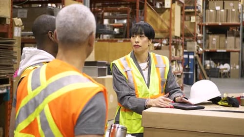 Warehouse team meeting with supervisor discussing shipping logistics