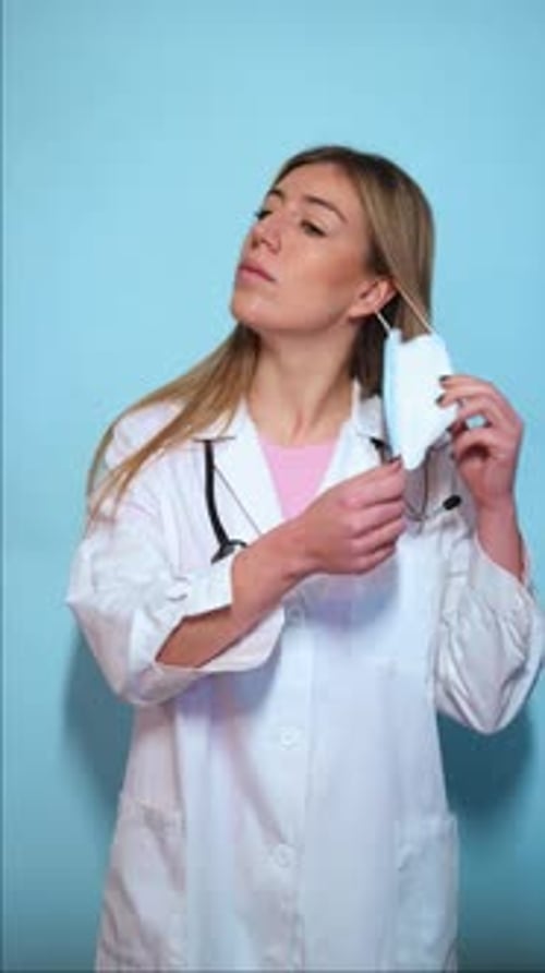 Female Doctor Removes Surgical Mask, Blue Background