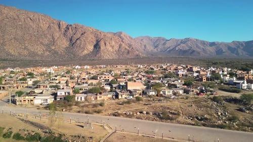 Aerial view drone flying over village with rocky mountains landscape and clear blue sky.
