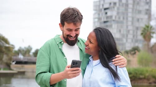 Happy Couple Laughing at Mobile Phone Outdoors