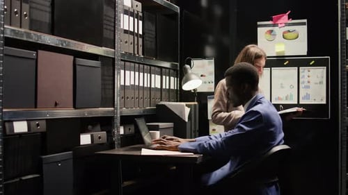 Coworkers Reviewing Data in Dimly Lit Office