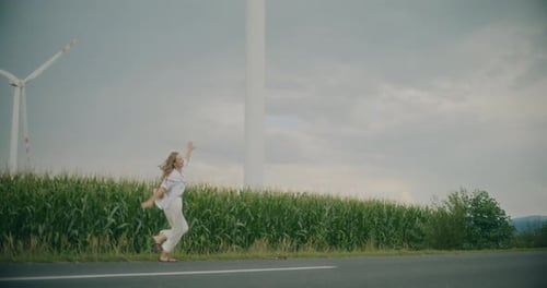 Woman Enjoying While Walking On Road Near Windfarm