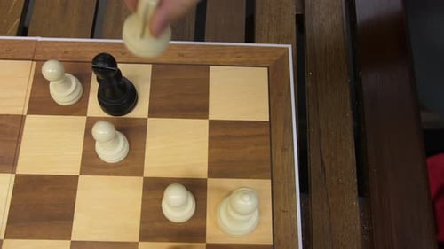 Schach, Ansicht von oben nach unten, weißer Bauer fängt schwarzen Bischof, Schachbrett auf Holztisch, Zeitlupe