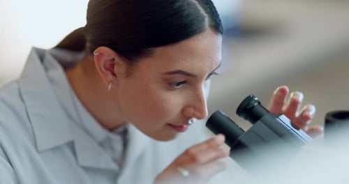 Young Woman Using Microscope in Bright Laboratory