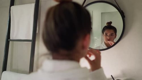 Woman Brushing Teeth in Minimalist Bathroom