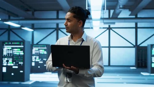 Technician Using Laptop in Data Center Managing Servers