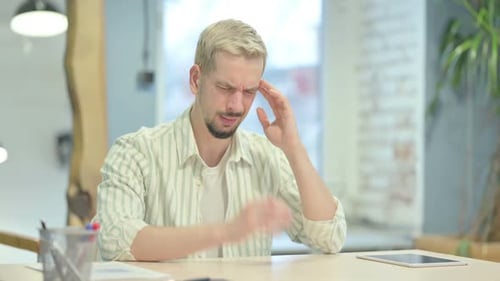 Man at Desk Rubbing Temples from Headache