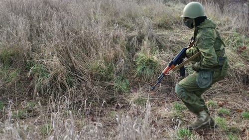 Soldier Kneeling and Reloading a Rifle in Field