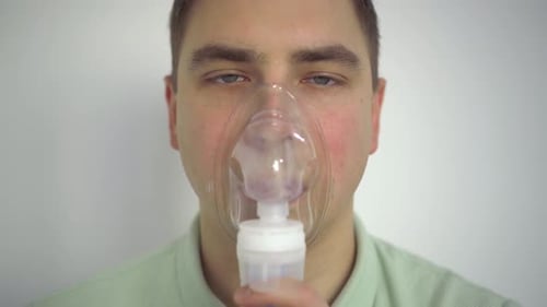 A Young Man Breathes Through an Inhaler Closeup A Man with an Oxygen Mask is Being Treated for a