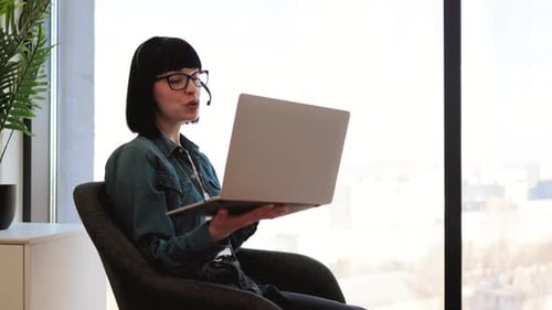 Woman on Video Call with Laptop in Modern Office
