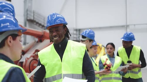 Gemischtrassige Ingenieure arbeiten in einer Automatisierungs- und Robotikanlage - Neue Industrietechnologie