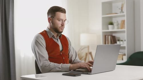 Young adult typing at laptop computer indoors
