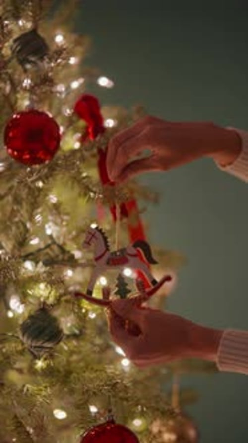 Hands Decorating Tree with White Wooden Horse Ornament