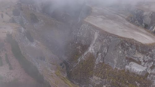 Aerial View of Low Hanging Clouds Drifting Across Deep Canyon Landscapes Revealing Rugged Andean