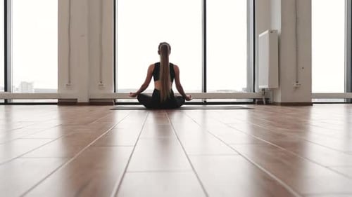 Female Meditating in Lotus Pose on Mat in Yoga Studio