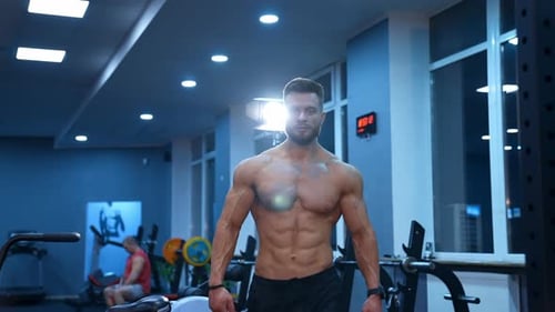Half length portrait of shirtless sportsman. Muscular bodybuilder with naked torso in the gym.