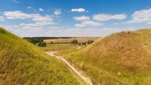 Delgado sendero que serpentea entre dos colinas en los prados. Sendero que conduce al pequeño estanque
.