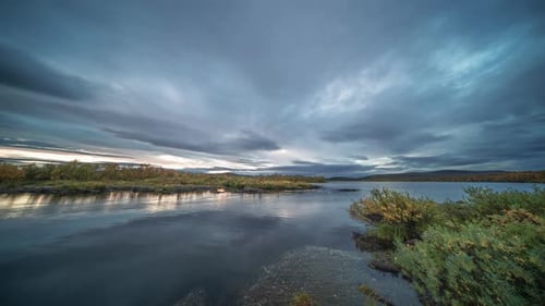 As darkness descends upon the landscape, stormy clouds move swiftly in the sunset skies.