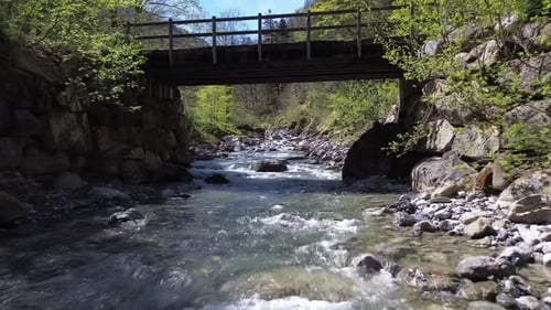 Drone Fly above River underneath Bridge in Idyllic Mountain Valley in Austria, Europe