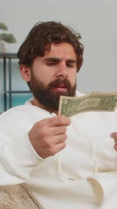 Man Seated Examining and Counting Currency Indoors