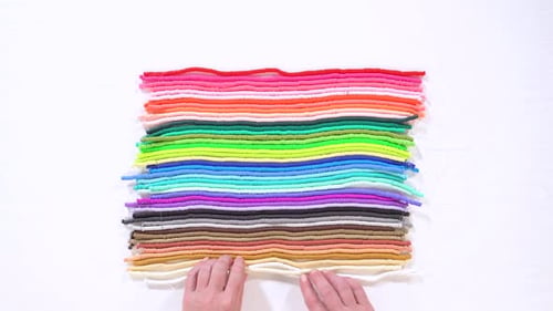 Hände weben sich durch bunte Tonperlenschnüre