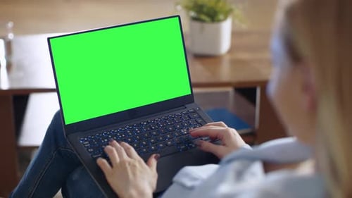 Long Shot of a Smiling Beautiful Woman Sitting on a Couch in Her Living Room. She Works on Her Lapt