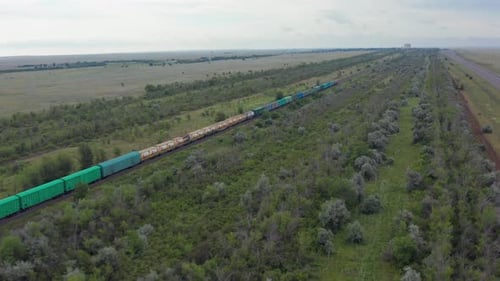 Aerial View Freight Train with Colorful Wagons Moving Across Green Countryside
