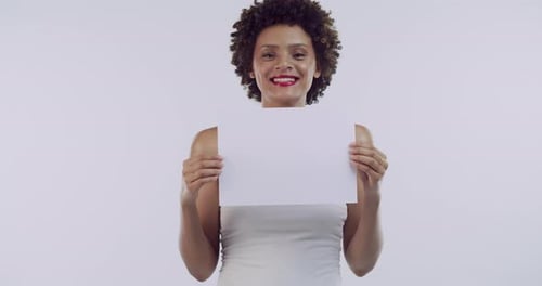 A beautiful young woman holding a blank sign against a grey studio background