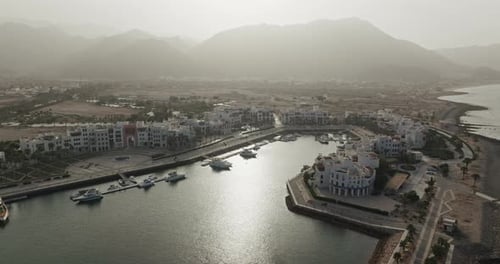 Ultra Wide Aerial Drone View of Sifah Complex, Marina, Sea and Mountains, Oman